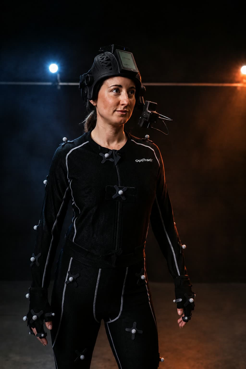 Full-body view of a performer in a marked OptiTrack suit and FACEGOOD SMART P3 facial capture helmet with the stereo camera boom in front of the face